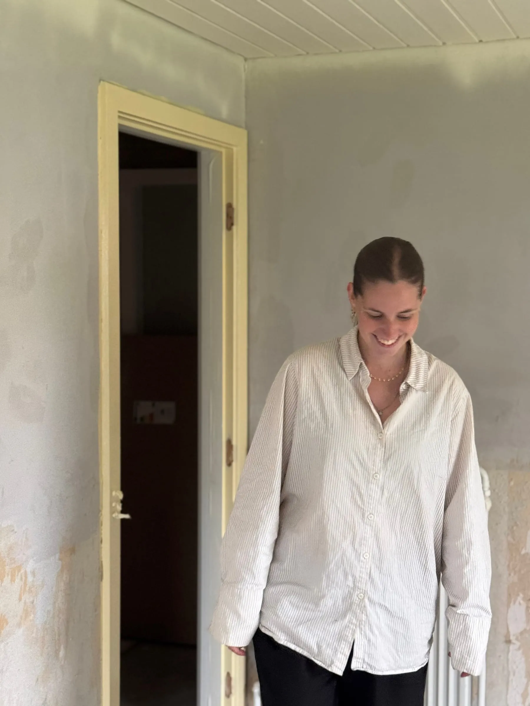 Sarah Tarp i et rum under renovering med afskrabede vægge